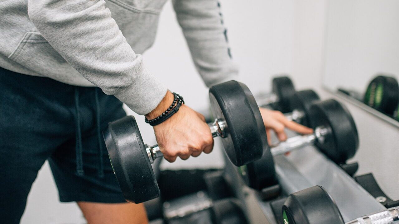 A man lifting a dumbbell during a workout in a gym