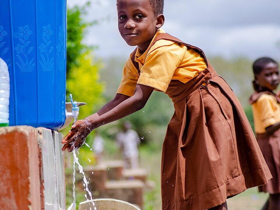 A school pupil washing her hands at an outdoor tap