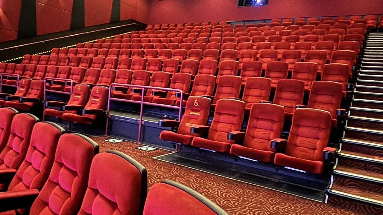 The interior of a movie theater auditorium with rows of red seats