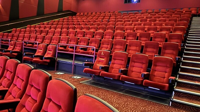 The interior of a movie theater auditorium with rows of red seats