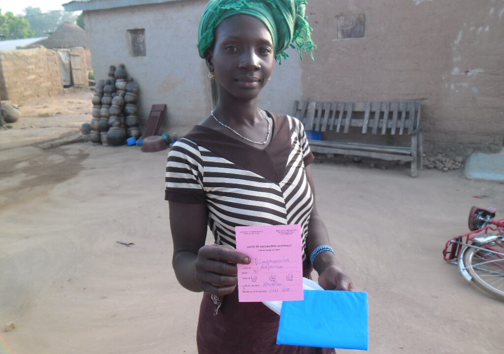 Mother holding her child measles vaccination card outdoors