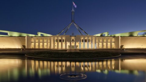 Parliament House Canberra illuminated at dusk with flag flying