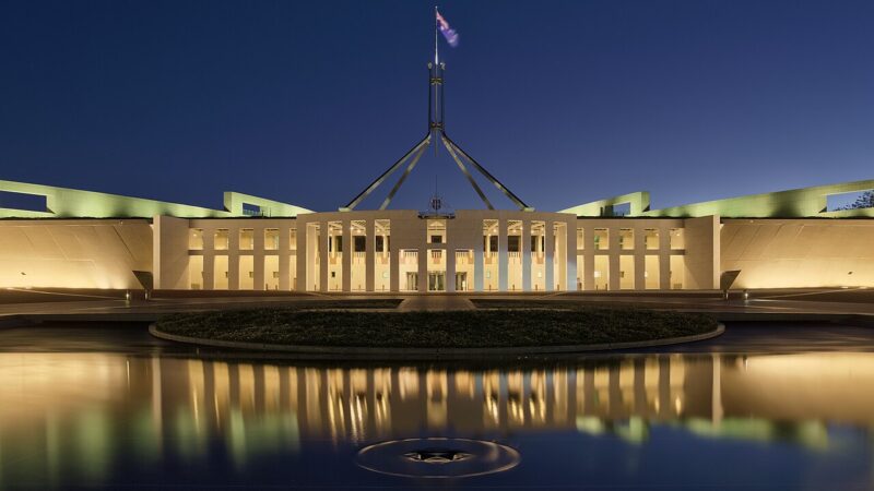 Parliament House Canberra illuminated at dusk with flag flying