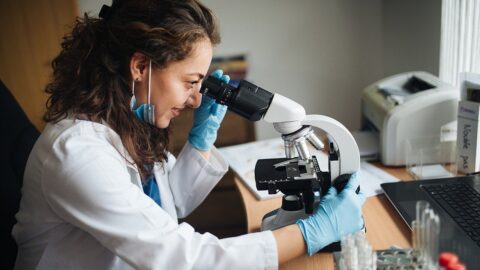 A laboratory technician examining a sample through a microscope