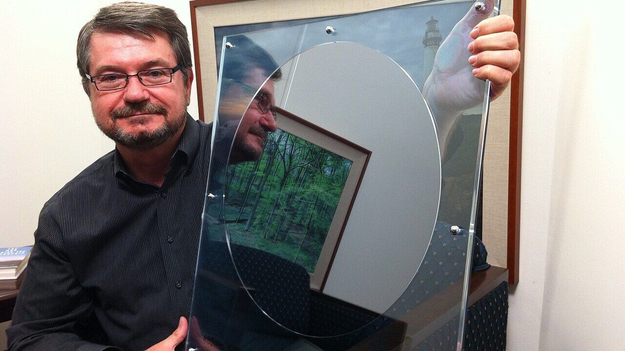 An engineer holding a large silicon wafer of the kind used to manufacture computer chips